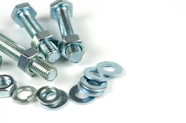 Metal cıvatalar ve fındıklar. Beyaz arka planda yuvarlak temizleyiciler var. Boşluğu kopyala