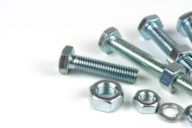 Metal cıvatalar ve fındıklar. Beyaz arka planda yuvarlak temizleyiciler var. Boşluğu kopyala