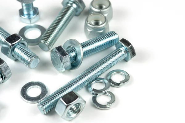 Metal cıvatalar ve fındıklar. Beyaz arka planda yuvarlak temizleyiciler var. Boşluğu kopyala