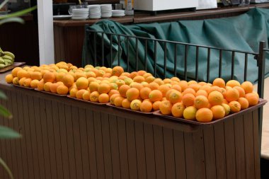 Dışarıdaki masada yığılmış portakallarla dolu tabaklar