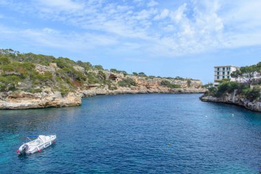 Cala Figuera Körfezi 'nin manzarası ve mavi sudaki motorlu tekne.