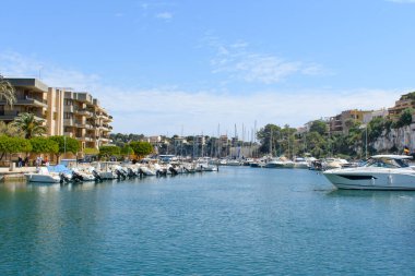 Porto Cristo, Mallorca, İspanya - 05.02.2022: Porto Cristo limanında yatlar ve tekneler. Arka planda kayalıklardaki evler