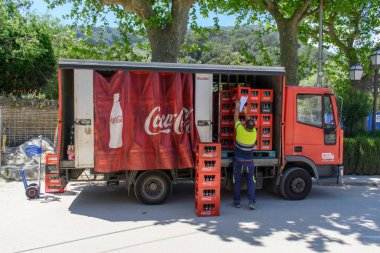 Valldemossa, Mallorca, Spain - 05.06.2022: Delivery man unloading Coca Cola crates from red truck clipart