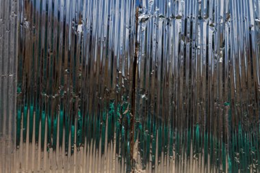 Oluklu alüminyum çarşaflardan yapılmış bir çitin yüzeyi.