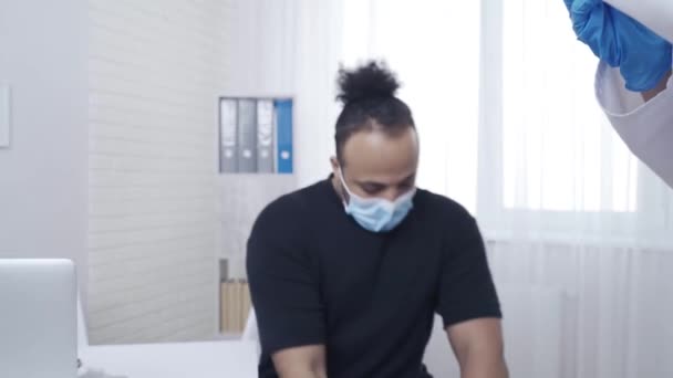 Lékař očkuje afroamerického pacienta v paži — Stock video