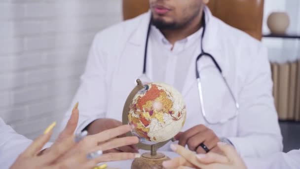 Médico afro-americano close-up com um globo, o conceito ithe ameaça de doenças em todo o mundo, em todo o mundo — Vídeo de Stock