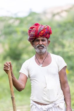 Jawai, Rajasthan, Hindistan - Eylül 2021: Jawai sahasında, ulusal başlık ve geleneksel beyaz elbise ve kırmızı sarıklı Rabari etnik grubunun yaşlı bir adamının portresi.