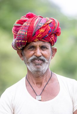 Jawai, Rajasthan, Hindistan - Eylül 2021: Jawai sahasında, ulusal başlık ve geleneksel beyaz elbise ve kırmızı sarıklı Rabari etnik grubunun yaşlı bir adamının portresi.