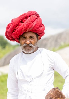 Jawai, Rajasthan, Hindistan - Eylül 2021: Jawai sahasında, ulusal başlık ve geleneksel beyaz elbise ve kırmızı sarıklı Rabari etnik grubunun yaşlı bir adamının portresi.