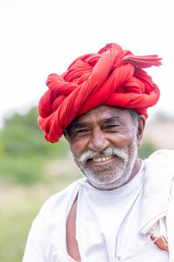 Jawai, Rajasthan, Hindistan - Eylül 2021: Jawai sahasında, ulusal başlık ve geleneksel beyaz elbise ve kırmızı sarıklı Rabari etnik grubunun yaşlı bir adamının portresi.