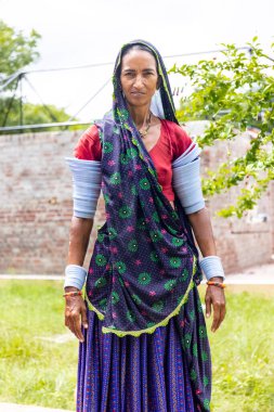 Jawai, Rajasthan, India - September 2021: Portrait of Indian woman working at construction site in ethnic rajasthani dress. Indian labour at working site.