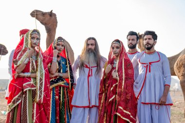 Puşkar, Rajasthan, Hindistan - Ekim 2019: Geleneksel Rajasthani ailesinin portre çekimi ve Pushkar Deve Fuarı 'nın arka planında develer