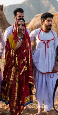 Puşkar, Rajasthan, Hindistan - Ekim 2019: Geleneksel Rajasthani ailesinin portre çekimi ve Pushkar Deve Fuarı 'nın arka planında develer