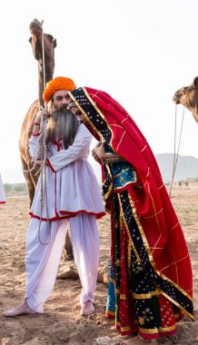 Puşkar, Rajasthan, Hindistan - Ekim 2019: Geleneksel Rajasthani ailesinin portre çekimi ve Pushkar Deve Fuarı 'nın arka planında develer
