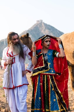 Puşkar, Rajasthan, Hindistan - Ekim 2019: Geleneksel Rajasthani ailesinin portre çekimi ve Pushkar Deve Fuarı 'nın arka planında develer