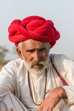 Puşkar, Rajasthan, Hindistan - Ekim 2017: Pushkar 'daki Deve Fuarında büyük bıyıklı Kırmızı Türbanlı Yaşlı Deve Taciri ve Beyaz Elbiseli