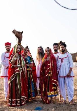 Puşkar, Rajasthan, Hindistan - Ekim 2019: Geleneksel Rajasthani ailesinin portre çekimi ve Pushkar Deve Fuarı 'nın arka planında develer