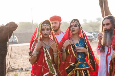 Puşkar, Rajasthan, Hindistan - Ekim 2019: Geleneksel Rajasthani ailesinin portre çekimi ve Pushkar Deve Fuarı 'nın arka planında develer