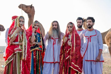 Puşkar, Rajasthan, Hindistan - Ekim 2019: Geleneksel Rajasthani ailesinin portre çekimi ve Pushkar Deve Fuarı 'nın arka planında develer