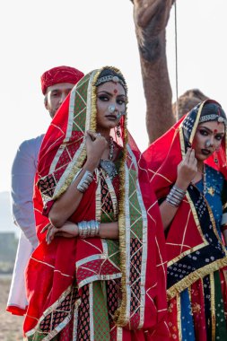 Puşkar, Rajasthan, Hindistan - Ekim 2019: Geleneksel Rajasthani ailesinin portre çekimi ve Pushkar Deve Fuarı 'nın arka planında develer