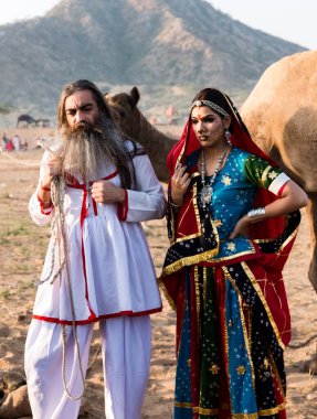 Puşkar, Rajasthan, Hindistan - Ekim 2019: Geleneksel Rajasthani ailesinin portre çekimi ve Pushkar Deve Fuarı 'nın arka planında develer