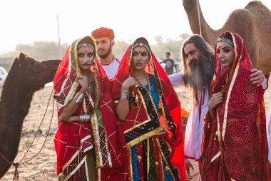 Puşkar, Rajasthan, Hindistan - Ekim 2019: Geleneksel Rajasthani ailesinin portre çekimi ve Pushkar Deve Fuarı 'nın arka planında develer