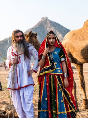 Puşkar, Rajasthan, Hindistan - Ekim 2019: Geleneksel Rajasthani ailesinin portre çekimi ve Pushkar Deve Fuarı 'nın arka planında develer