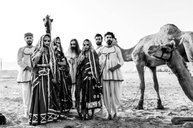 Puşkar, Rajasthan, Hindistan - Ekim 2019: Geleneksel Rajasthani ailesinin portre çekimi ve Pushkar Deve Fuarı 'nın arka planında develer