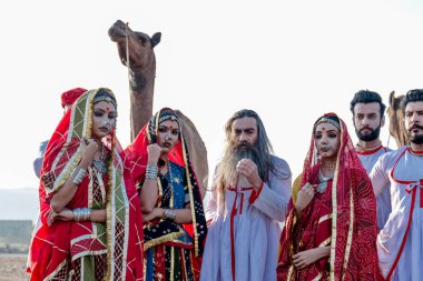 Puşkar, Rajasthan, Hindistan - Ekim 2019: Geleneksel Rajasthani ailesinin portre çekimi ve Pushkar Deve Fuarı 'nın arka planında develer