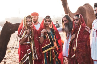 Puşkar, Rajasthan, Hindistan - Ekim 2019: Geleneksel Rajasthani ailesinin portre çekimi ve Pushkar Deve Fuarı 'nın arka planında develer