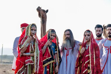 Puşkar, Rajasthan, Hindistan - Ekim 2019: Geleneksel Rajasthani ailesinin portre çekimi ve Pushkar Deve Fuarı 'nın arka planında develer