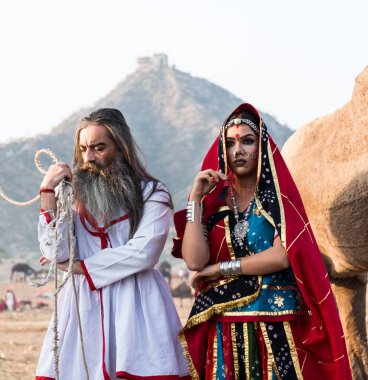 Puşkar, Rajasthan, Hindistan - Ekim 2019: Geleneksel Rajasthani ailesinin portre çekimi ve Pushkar Deve Fuarı 'nın arka planında develer