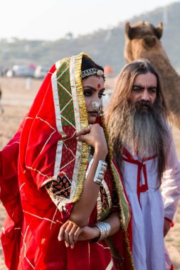 Puşkar, Rajasthan, Hindistan - Ekim 2019: Geleneksel Rajasthani ailesinin portre çekimi ve Pushkar Deve Fuarı 'nın arka planında develer