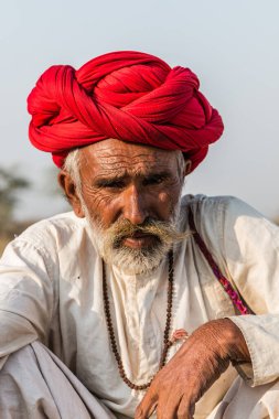 Puşkar, Rajasthan, Hindistan - Ekim 2017: Pushkar 'daki Deve Fuarında büyük bıyıklı Kırmızı Türbanlı Yaşlı Deve Taciri ve Beyaz Elbiseli