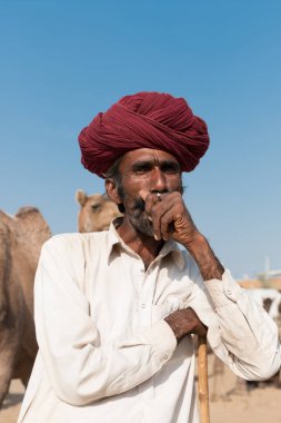 Puşkar, Rajasthan, Hindistan - Ekim 2017: Rajasthan 'lı Hintli adam fuar sırasında açık arazide sigara içiyor