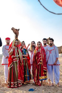 Puşkar, Rajasthan, Hindistan - Ekim 2019: Geleneksel Rajasthani ailesinin portre çekimi ve Pushkar Deve Fuarı 'nın arka planında develer