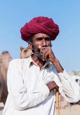 Puşkar, Rajasthan, Hindistan - Ekim 2017: Rajasthan 'lı Hintli adam fuar sırasında açık arazide sigara içiyor