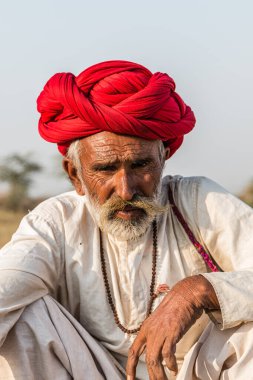 Puşkar, Rajasthan, Hindistan - Ekim 2017: Pushkar 'daki Deve Fuarında büyük bıyıklı Kırmızı Türbanlı Yaşlı Deve Taciri ve Beyaz Elbiseli