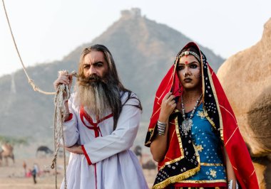 Puşkar, Rajasthan, Hindistan - Ekim 2019: Geleneksel Rajasthani ailesinin portre çekimi ve Pushkar Deve Fuarı 'nın arka planında develer