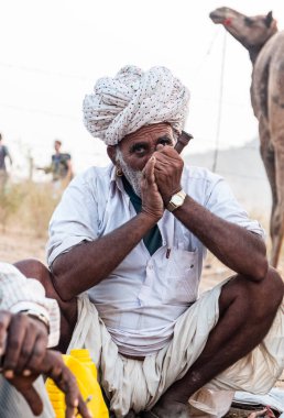 Puşkar, Rajasthan, Hindistan - Ekim 2017: Rajasthan 'lı Hintli adam fuar sırasında açık arazide sigara içiyor