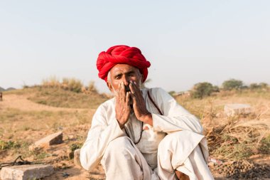 Puşkar, Rajasthan, Hindistan - Ekim 2017: Pushkar 'daki Deve Fuarında büyük bıyıklı Kırmızı Türbanlı Yaşlı Deve Taciri ve Beyaz Elbiseli