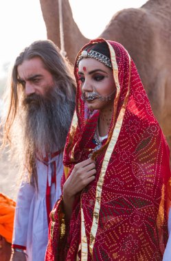 Puşkar, Rajasthan, Hindistan - Ekim 2019: Geleneksel Rajasthani ailesinin portre çekimi ve Pushkar Deve Fuarı 'nın arka planında develer