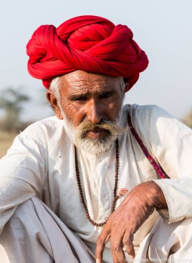 Puşkar, Rajasthan, Hindistan - Ekim 2017: Pushkar 'daki Deve Fuarında büyük bıyıklı Kırmızı Türbanlı Yaşlı Deve Taciri ve Beyaz Elbiseli
