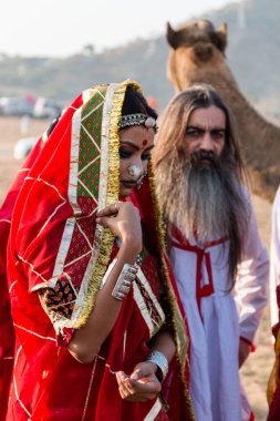 Puşkar, Rajasthan, Hindistan - Ekim 2019: Geleneksel Rajasthani ailesinin portre çekimi ve Pushkar Deve Fuarı 'nın arka planında develer