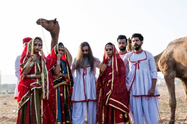 Puşkar, Rajasthan, Hindistan - Ekim 2019: Geleneksel Rajasthani ailesinin portre çekimi ve Pushkar Deve Fuarı 'nın arka planında develer