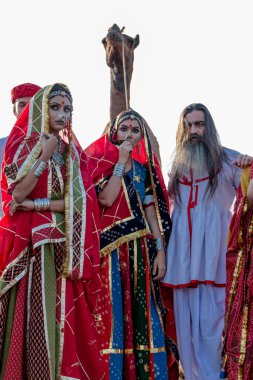 Puşkar, Rajasthan, Hindistan - Ekim 2019: Geleneksel Rajasthani ailesinin portre çekimi ve Pushkar Deve Fuarı 'nın arka planında develer