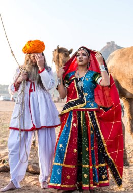 Puşkar, Rajasthan, Hindistan - Ekim 2019: Geleneksel Rajasthani ailesinin portre çekimi ve Pushkar Deve Fuarı 'nın arka planında develer