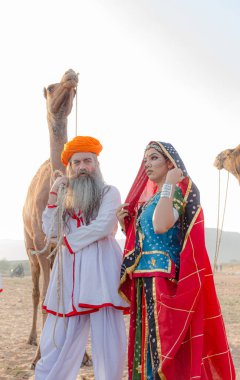 Puşkar, Rajasthan, Hindistan - Ekim 2019: Geleneksel Rajasthani ailesinin portre çekimi ve Pushkar Deve Fuarı 'nın arka planında develer