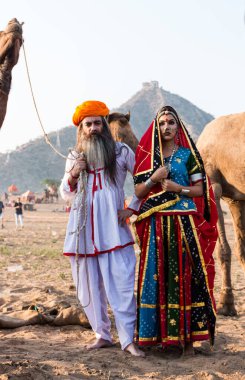 Puşkar, Rajasthan, Hindistan - Ekim 2019: Geleneksel Rajasthani ailesinin portre çekimi ve Pushkar Deve Fuarı 'nın arka planında develer