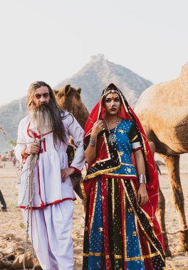 Puşkar, Rajasthan, Hindistan - Ekim 2019: Geleneksel Rajasthani ailesinin portre çekimi ve Pushkar Deve Fuarı 'nın arka planında develer